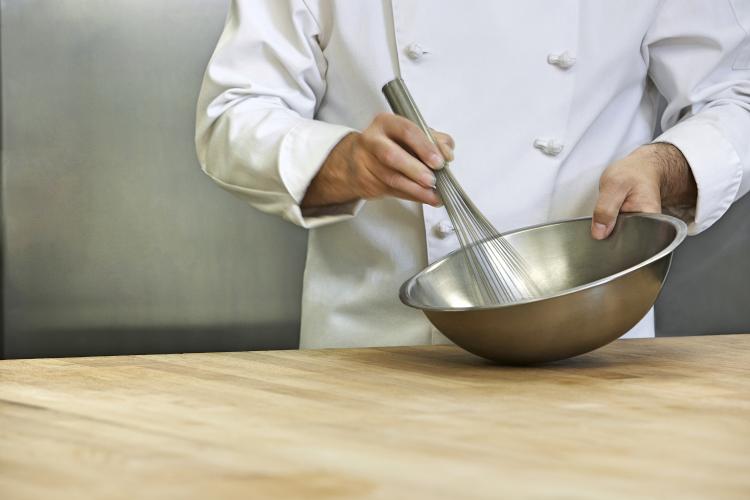 Chef mixing ingredients with whisk in bowl